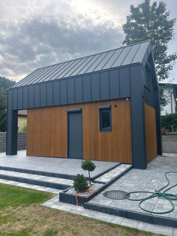 Ekodom50: widok na patio i mały ogród w pochmurny dzień.