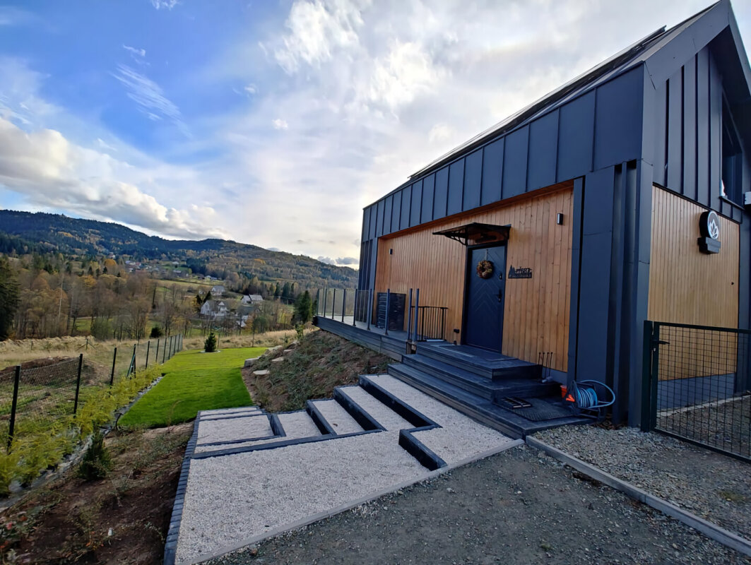Modernes Skeletthaus, Eingang mit Vordach, Holzfassade in Bergbauumgebung.