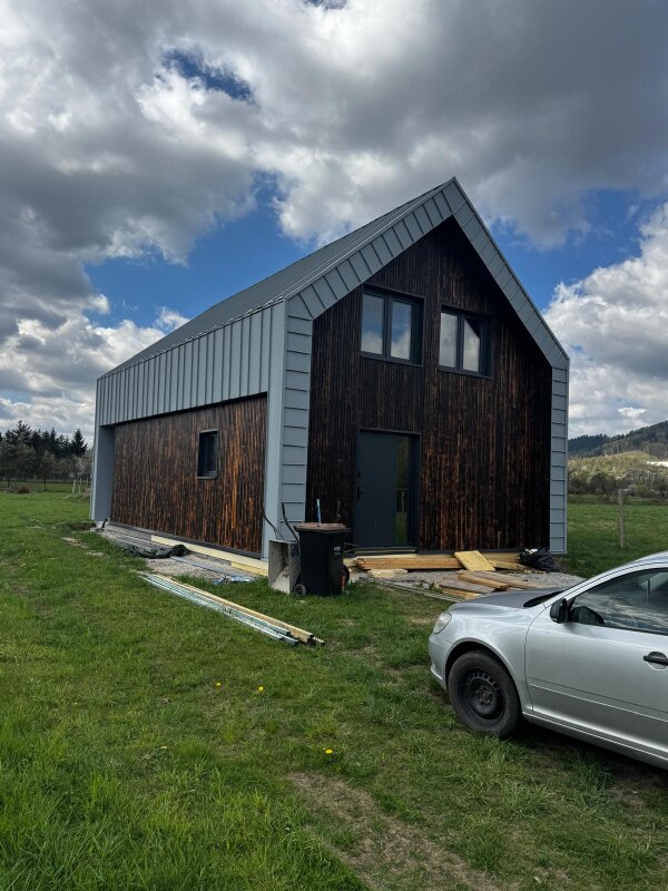 Dom szkieletowy w Cięcinie z elewacją z ciemnego drewna i dachem krytym blachą na rąbek