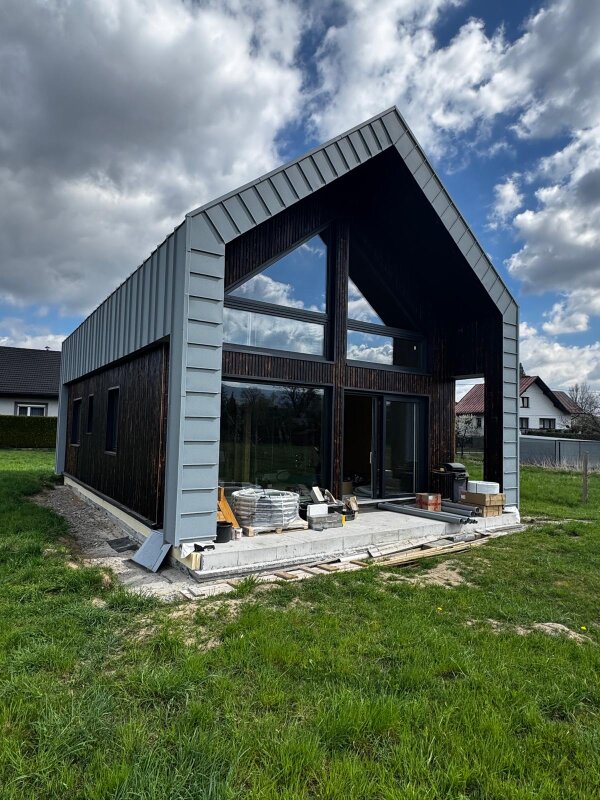 Frontowa ściana domu szkieletowego z dużymi przeszkleniami i konstrukcją z drewna C24