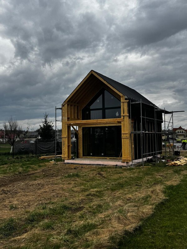 Etap budowy domu szkieletowego w Cięcinie z widocznym szkieletem z drewna C24 oraz czarną folią wiatroizolacyjną
