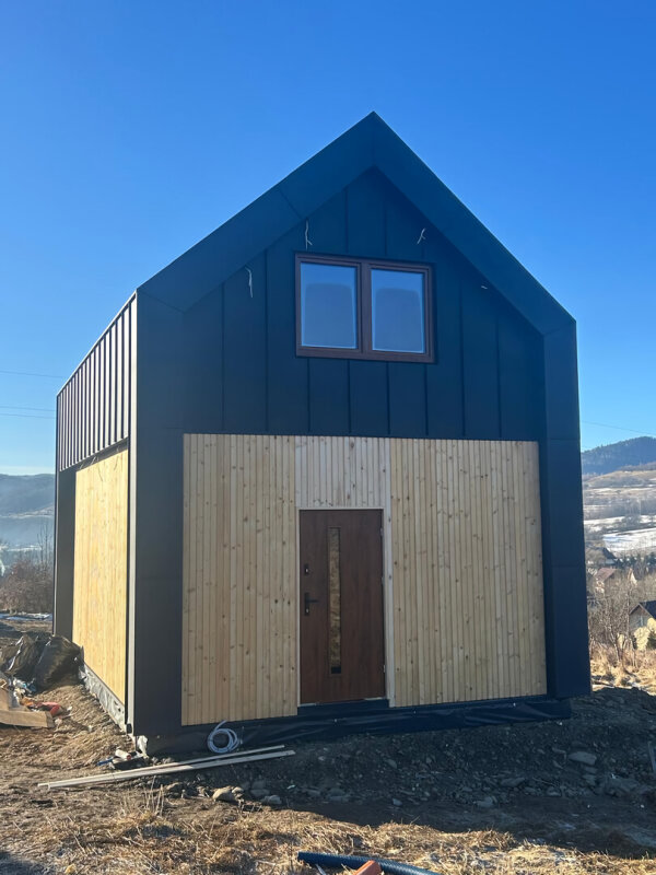 Front of Ekodom 50 house, entrance door, wood and black metal cladding.