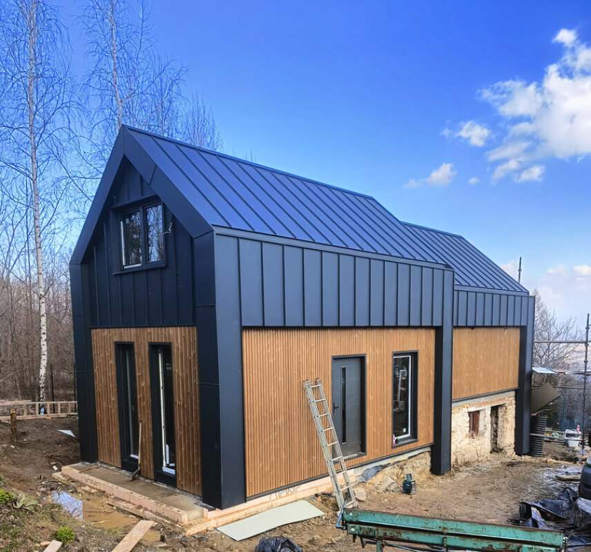 Matyska timber frame house; thermo pine facade and black standing seam metal sheet.