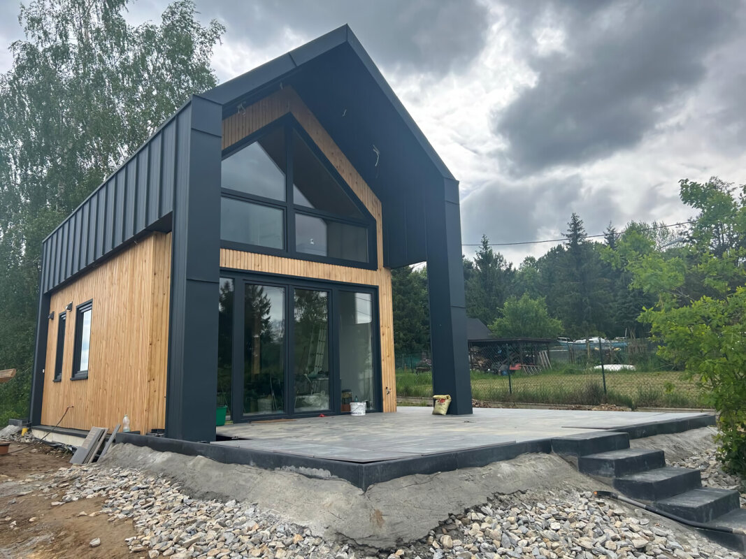 Fassade des Holzrahmenhauses Ekodom 50; Fassadenverkleidung aus Holz und Blech; große Fenster.