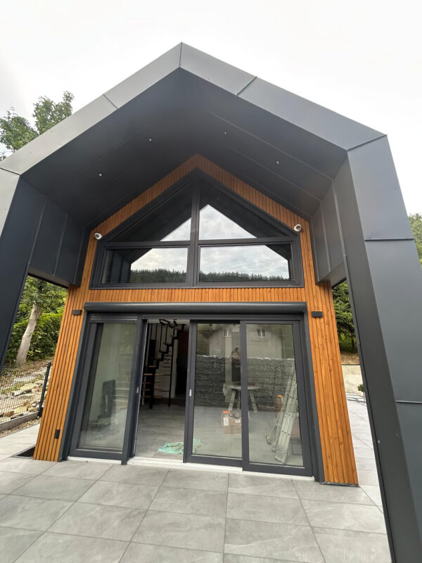 Duże przeszklenia i drzwi tarasowe w szczycie nowoczesnego domu Ekodom 50.