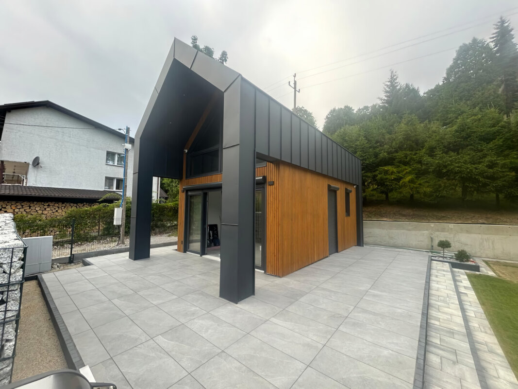 Dom szkieletowy Ekodom 50 z dużym tarasem, czarna blacha i drewniana elewacja.