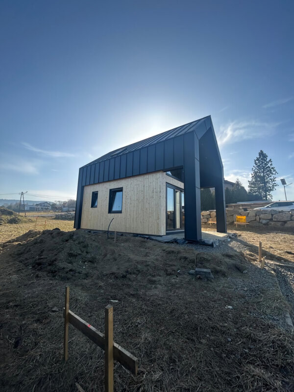 Ekodom 50: timber frame house on a hill, wooden/metal facade, construction stage.