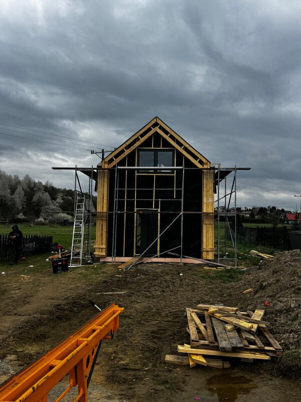 Widok szczytowej ściany domu szkieletowego w trakcie prac montażowych na placu budowy w Polance Wielkiej