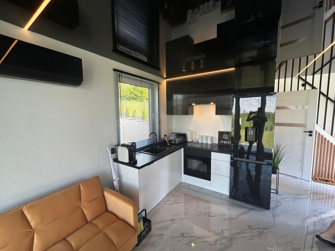 Kitchenette moderne maison modulaire. Armoires noires et blanches, efficacité énergétique.