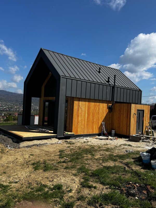 Widok na konstrukcję domu szkieletowego Ekodom75 z drewnianym tarasem w piękny słoneczny dzień