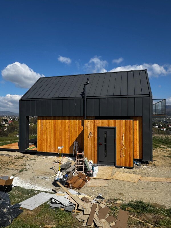 Elewacja domu szkieletowego w Pietrzykowicach wykończona modrzewiową deską oraz ciemną blachą na rąbek