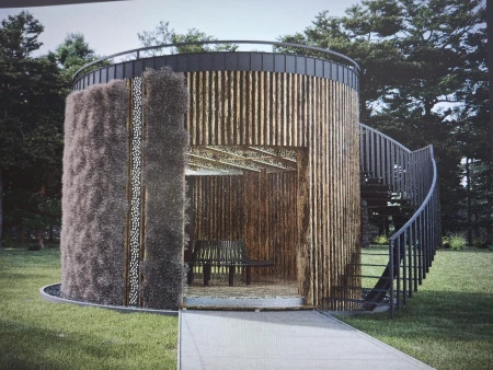 Wizualizacja nowoczesnej, cylindrycznej tężni solankowej Salty rest w zielonym otoczeniu. Tężnia charakteryzuje się fasadą z naturalnego drewna i ciemnymi ścianami z tarniny. Z boku widoczne są spiralne schody prowadzące na dach, a wewnątrz obiektu znajduje się ławka. Całość otoczona jest trawnikiem i drzewami, co podkreśla jej integrację z naturą.