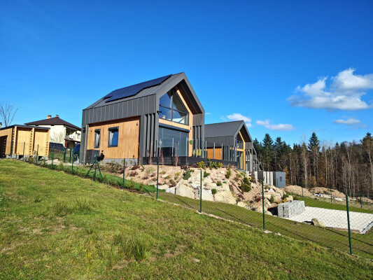 Domy modułowe (9 sztuk) w Pewli Wielkiej; fasada drewniana/blacha, panele fotowoltaiczne, konstrukcja szkieletowa.