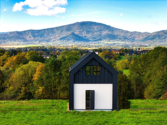 Modular timber-frame house Ekodom 50 in Bierna against a mountain backdrop; modern form and large glazing.