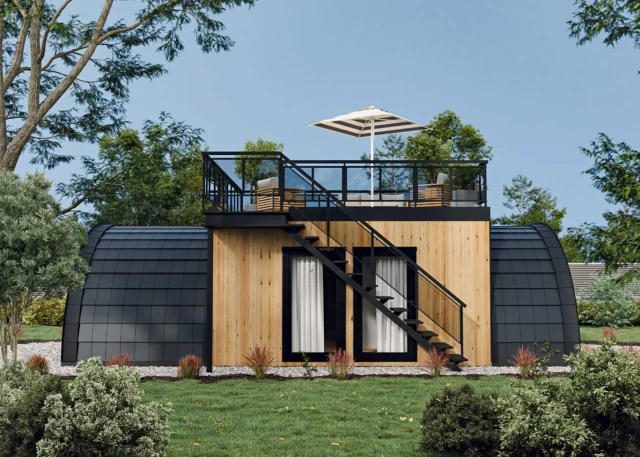 Nowoczesny dom modułowy z drewnianą elewacją i ciemnym, łukowatym dachem, w naturalnym otoczeniu.
